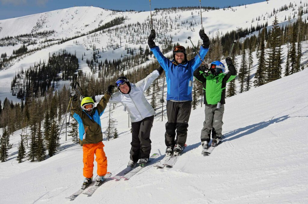 Family of four skiing on Schweitzer Mountain smiling and posing