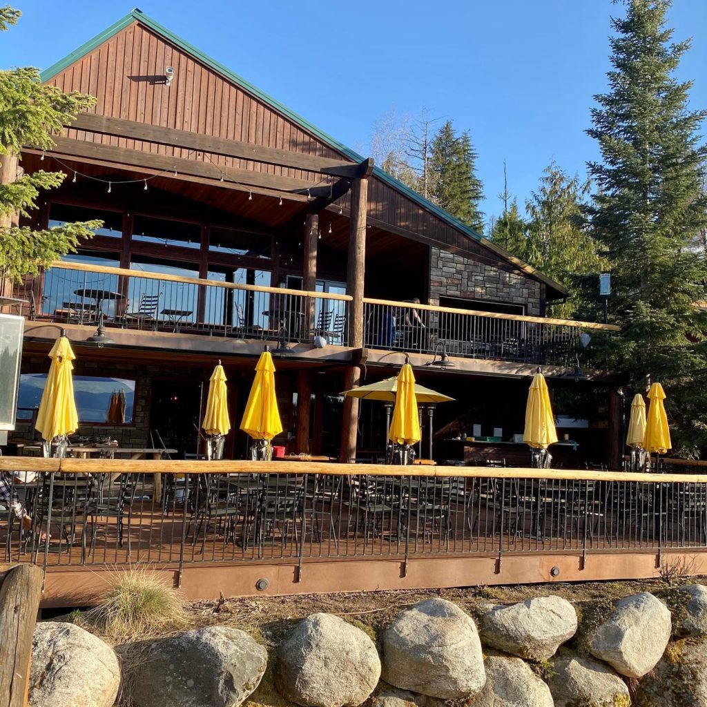 large outdoor patio seating with yellow umbrellas at the Cavanaugh Bay resort Priest Lake deck restaurant bar in Coolin, Idaho