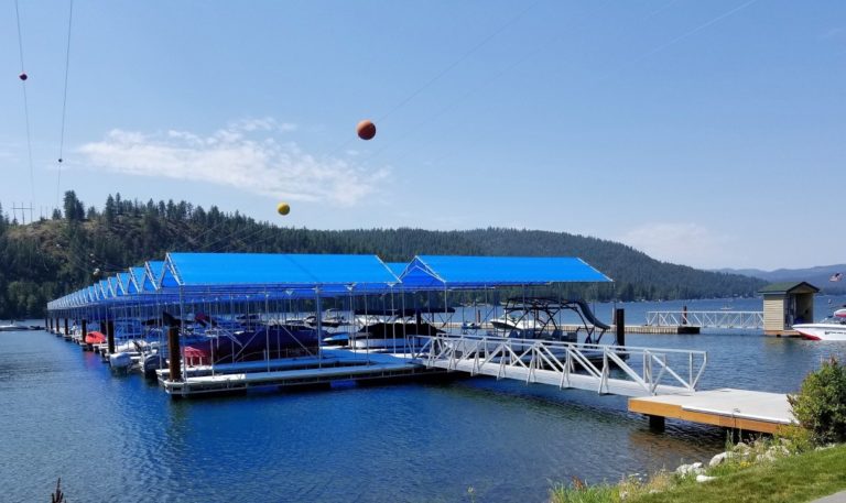 Boat moors with blue tops and docks on the lake shore at Dover Bay Marina on the Pend Oreille River