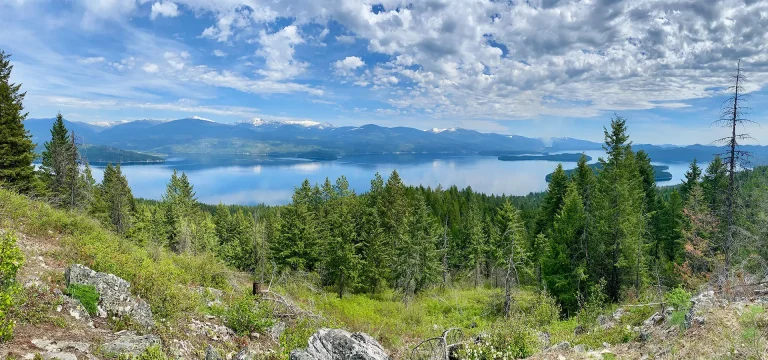 panorama view of Priest Lake blue skies with clouds, trees